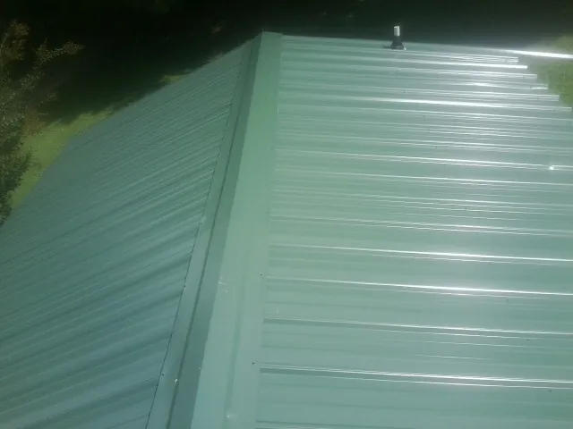 New green metal panels meeting at the ridge of a roof — Flat Roof Repair work by our crew in Mount Hermon