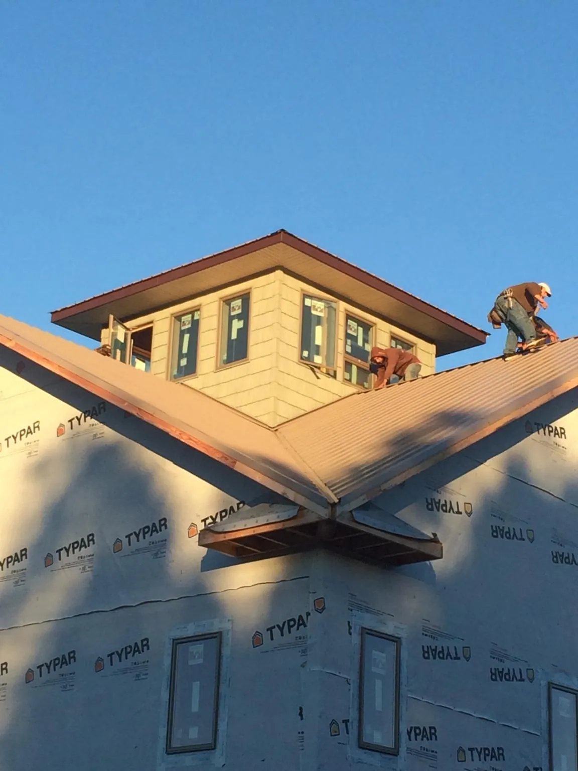 Roofers working around a rooftop cupola on a new metal roof at sunset — Roof Waterproofing in Mount Hermon by Roofing Brothers
